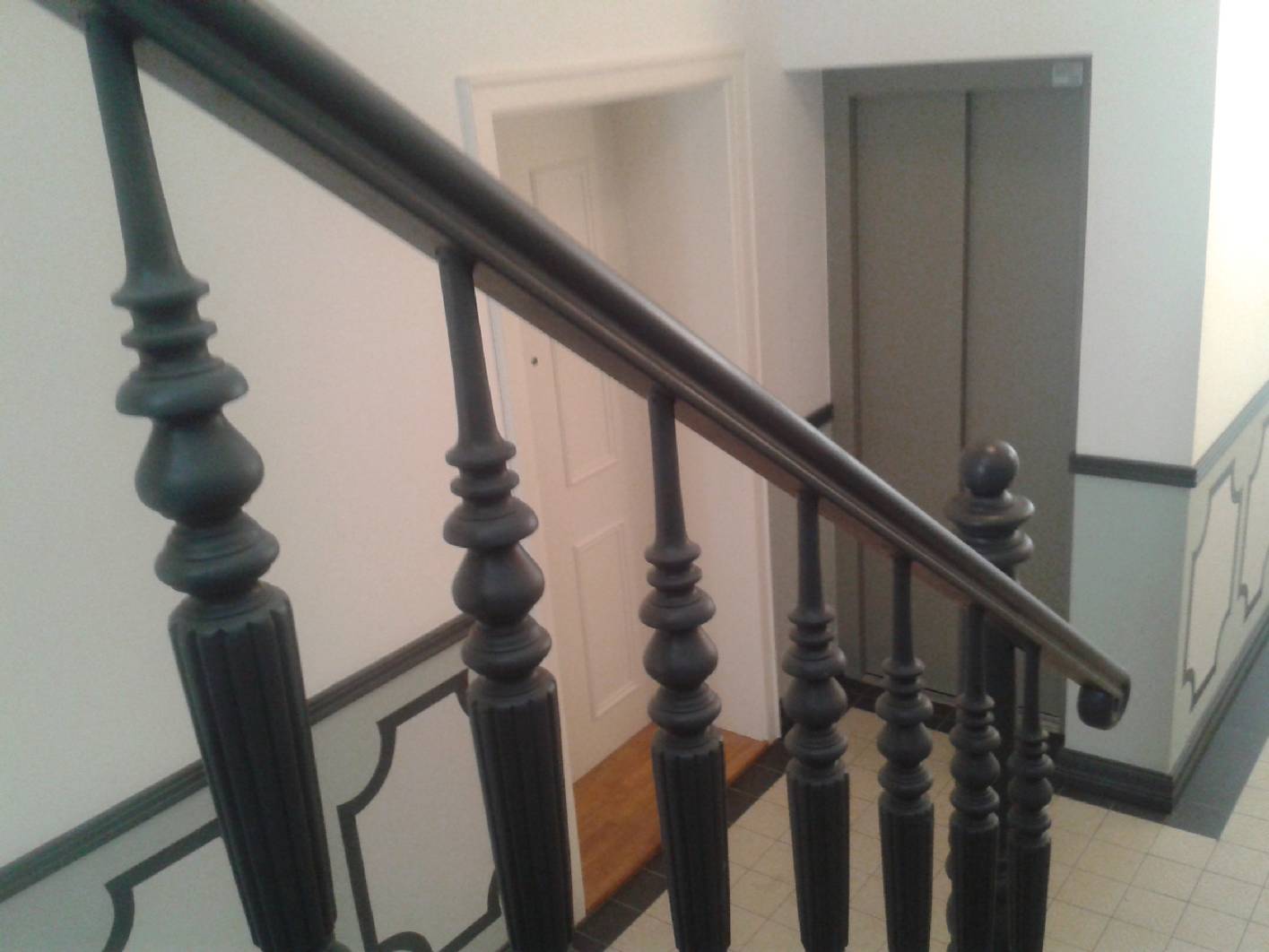 Ansicht zum Eingangsbereich und zum innenliegenden Fahrstuhl. Das Gründerzeit Treppenhaus wurde komplett Kernsaniert im Eingangsbereich ist ein Paneel mit Schablonen zu sehen. Das Anbringen der Paneelleiste und des Fußbodens gehört auch mit zu unseren Aufgabenbereich Gesamtkonzept Treppenhaus. Hierfür habe ich meine Maler über die gewöhnlichen Malerarbeiten weiter geschult.